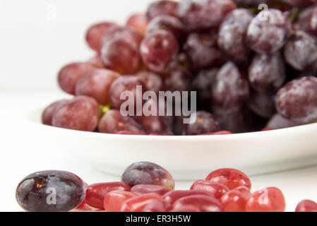 Les raisins de pourpre violet vs jelly beans - snack-décision entre aliments sains ou junk food Banque D'Images