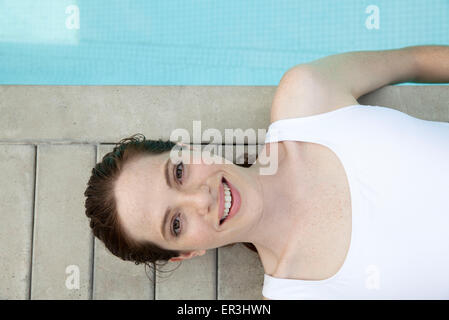 Jeune femme au soleil au bord de piscine, smiling, portrait Banque D'Images