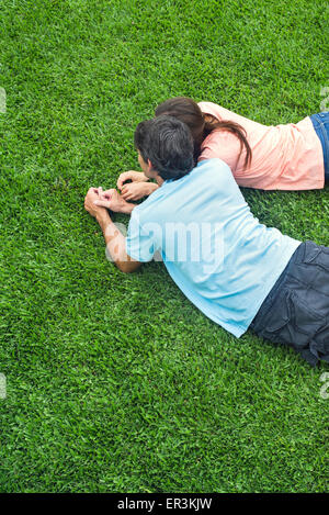 Couple lying together on grass Banque D'Images