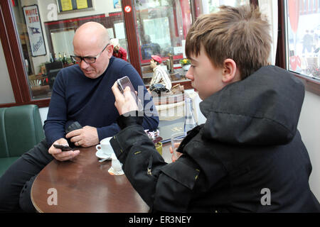 Père et fils en utilisant leur téléphone mobile in coffee shop Banque D'Images