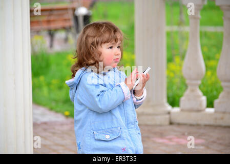 Little girl talking on cell phone contre green Park de en été. Banque D'Images