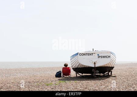 Femme assise sur la plage à côté de voile nommé content Banque D'Images