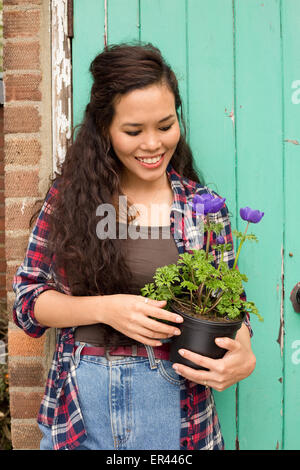 Une jeune femme tenant une plante en pot dans le jardin. Banque D'Images