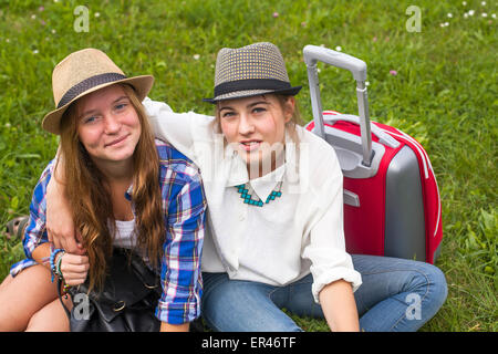 Deux jeunes filles amies voyageurs, assis sur l'herbe. Banque D'Images