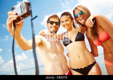 Amis heureux de prendre des photos sur la plage Banque D'Images