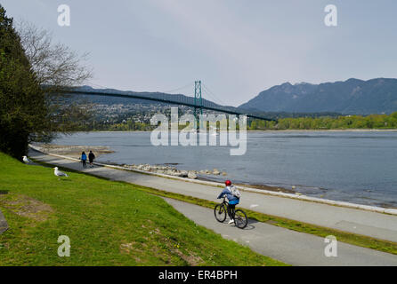 Les gens le vélo et la marche le long du sentier côtier du parc Stanley à Vancouver. Lion's Gate Bridge, l'Inlet Burrard, et les montagnes du North Shore. Banque D'Images