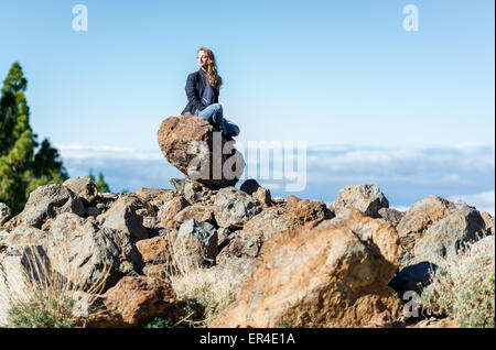 Femme assise sur un rocher Banque D'Images