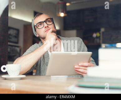 Dreaming man using digital tablet at cafe. Cracovie, Pologne Banque D'Images