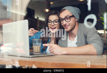 S'amuser en couple à la recherche sur l'ordinateur portable au café. Cracovie, Pologne Banque D'Images