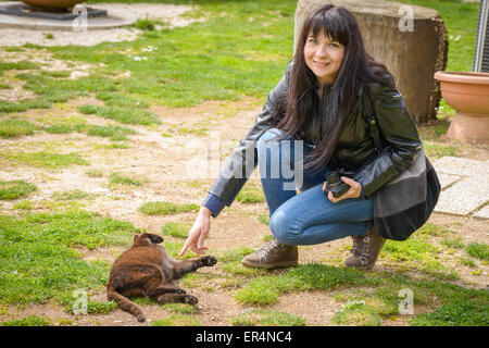 Une fille jouant dans un jardin avec un chat noir Banque D'Images