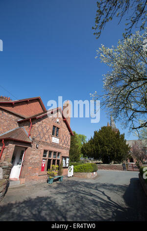 Village de Aldford, Angleterre. Printemps pittoresque vue du village store avec St Jean Baptiste l'église de l'arrière-plan. Banque D'Images