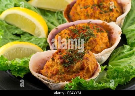 Les palourdes farcies garnies de laitue romaine et les quartiers de citron sur une assiette rustique Banque D'Images