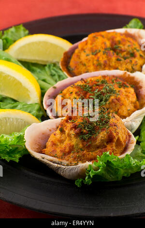 Les palourdes farcies garnies de laitue romaine et les quartiers de citron sur une assiette rustique Banque D'Images