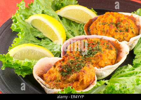 Les palourdes farcies garnies de laitue romaine et les quartiers de citron sur une assiette rustique Banque D'Images