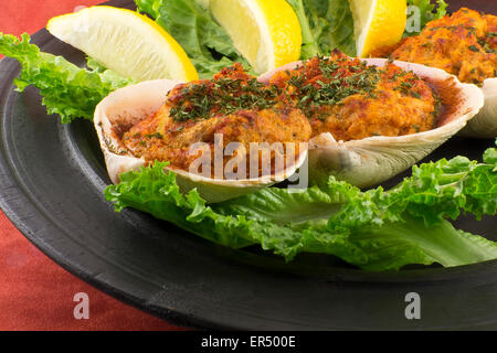 Les palourdes farcies garnies de laitue romaine et les quartiers de citron sur une assiette rustique Banque D'Images