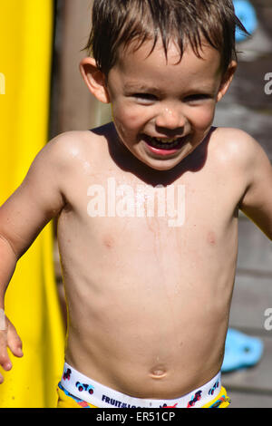 Un jeune garçon de l'été, tout en souriant jouant dans l'eau.