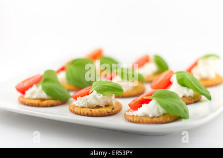 Plaque snack de craquelins garnies de fromage ricotta et basilic tomates Banque D'Images