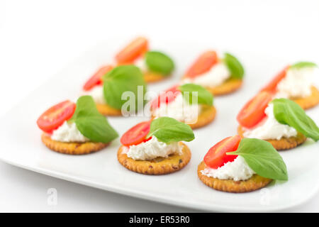 Plaque snack de craquelins garnies de fromage ricotta et basilic tomates Banque D'Images