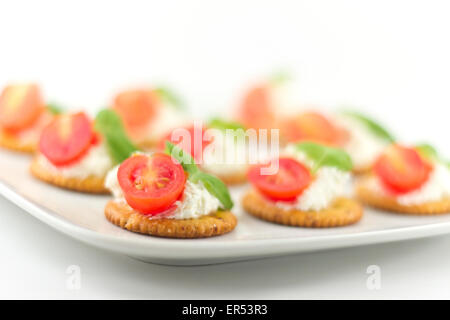 Plaque snack de craquelins garnies de fromage ricotta et basilic tomates Banque D'Images