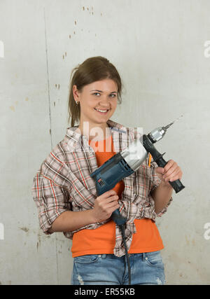 Blond woman holding electric drill and smiling Banque D'Images