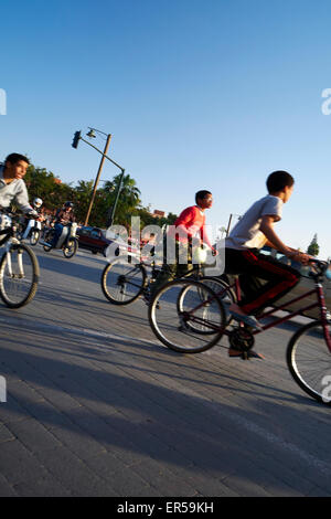 Les enfants à vélo à un rond-point de Marrakech, Maroc Banque D'Images