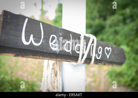 Flèche en bois gris avec un signe de mariage et coeur écrit à la craie Banque D'Images