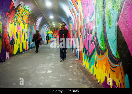 Les voyageurs passent par les 900 pieds de long tunnel reliant la station de métro 191e, récemment décorées par des artistes engagés par le nouveau ministère des Transports de la ville de New York le Jeudi, Mai 21, 2015. Les artistes, FAIRE FACE2, Queen Andrea, Nick, Cekis Kuszyk et Jessie Unterhalter et Katey Truhn ont été choisis dans un processus concurrentiel par le point. Le tunnel a récemment reçu l'éclairage à LED et mis à niveau avec l'ajout des murales a été transformé en galerie d'art. (© Richard B. Levine) Banque D'Images