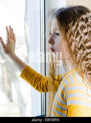 Enfant triste regarde par la fenêtre Banque D'Images