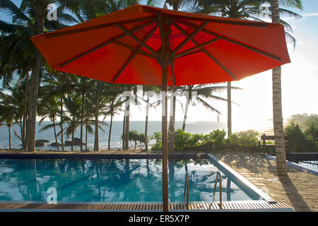 Parasol et la piscine sous les palmiers avec vue sur la mer, l'Hôtel de la Baie aux Tortues, Tangalle, Sri Lanka Banque D'Images