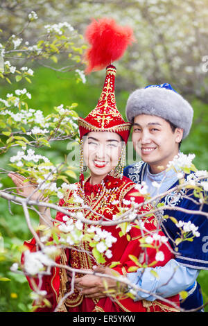 Heureux couple en costumes Kazakh au printemps fleurs jardin apple d'Almaty, Kazakhstan, en Asie centrale Banque D'Images