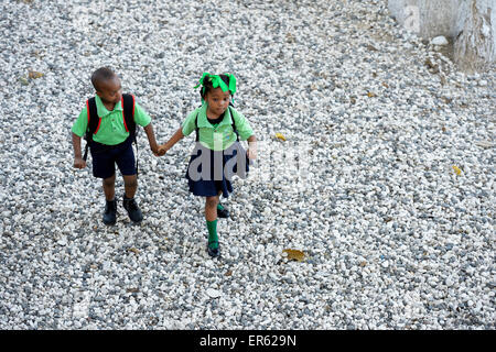 Garçon et fille, frères et sœurs, se tenant la main sur le chemin de l'école maternelle, Port-au-Prince, Haïti, Département de l'Ouest. Banque D'Images