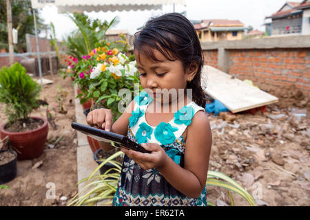 Petite fille jouant avec un ordinateur tablette, Phnom Penh, Cambodge Banque D'Images