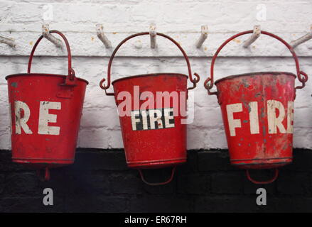 Une rangée de seaux d'incendie vintage accrocher de suite, England, UK Banque D'Images