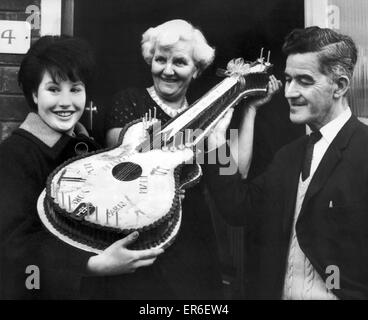 Fan des Beatles, Jeanette Trust 16 de West Derby, Liverpool, présente Harold et Louise Harrison, les parents de George Harrison, avec un gâteau en forme de guitare, qu'elle a aidé à faire, pour célébrer son 21e anniversaire. Sur la photo 25 février 1964. Banque D'Images