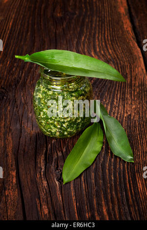 Pesto à l'ail avec de l'ail sauvage feuilles sur fond texturé en bois brun. Culinary alimentation saine. Banque D'Images