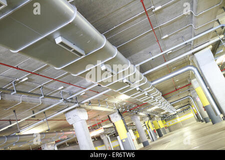 Parc souterrain d'un centre commercial avec des colonnes et des conduits de ventilation Banque D'Images