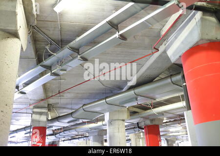 Parc souterrain d'un centre commercial avec des colonnes et des conduits de ventilation Banque D'Images