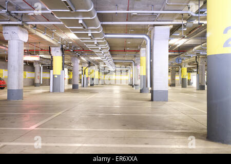 Parc souterrain d'un centre commercial avec des colonnes et des conduits de ventilation Banque D'Images