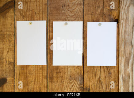 Feuilles de papier blanc fixé sur la paroi en bois avec les punaises Banque D'Images