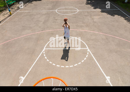 Portrait de jeune homme athlétique de détritus en tenant tourné sur le bénéfice net à partir de la ligne de touche du terrain de basket-ball extérieur Banque D'Images