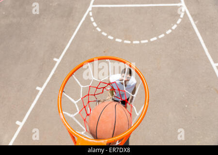 Portrait de jeune homme athlétique de détritus faisant tourné sur le Net de basket-ball en plein air aux beaux jours Banque D'Images