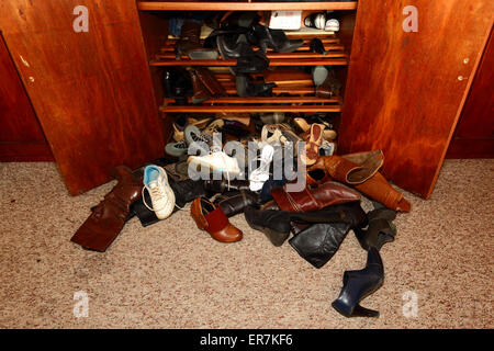 Sélection de womens shoes untidily éparpillés sur le sol à l'avant de l'armoire dans la chambre Banque D'Images