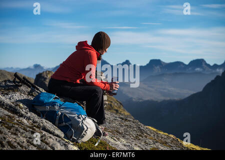 Female hiker prend une pause et jouit d'une vue sur la montagne, Moskenesøy, îles Lofoten, Norvège Banque D'Images