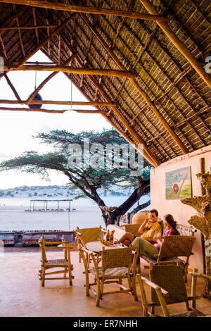 L'ÎLE DE MANDA, Lamu, l'OCÉAN INDIEN, le KENYA, l'Afrique. Un homme et une femme s'asseoir sur un toit de chaume salon donnant sur une plage d'Afrique. Banque D'Images