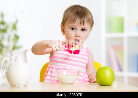 Little girl eating corn flakes avec du lait à table dans la maison Banque D'Images