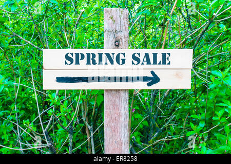 Vente de printemps written sur panneau en bois avec la flèche pointant vers la droite contre vert feuilles arrière-plan. Concept image avec copie espace disponible Banque D'Images