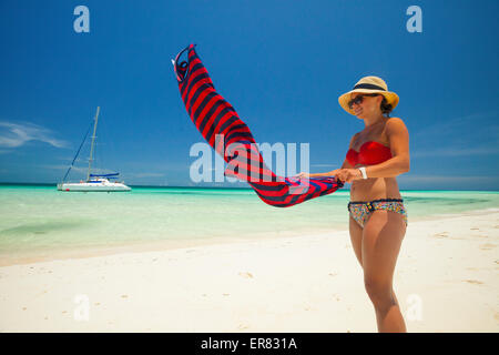 Une jeune femme secoue le sable au large de sa robe d'été tout en profitant d'une belle plage à Cuba. Banque D'Images