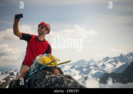 Un grimpeur prend un smartphone selfies avec son trio au sommet du pic. Banque D'Images