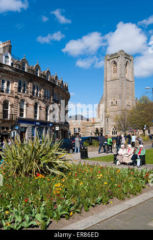 Les gens assis dehors dans le centre-ville de Harrogate et l'église St Peters à Spring Harrogate North Yorkshire Angleterre Royaume-Uni Grande-Bretagne Banque D'Images