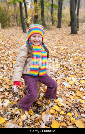 Girl sitting on stump in autumn park Banque D'Images